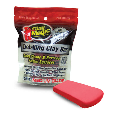 A package of AutoMagic Clay Magic Red Detailing Clay Bar, with the product visible in the foreground. The package has red and white colors with product information printed on it.
